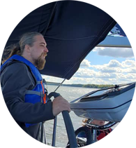 Headshot of Ben steering a sailboat.
